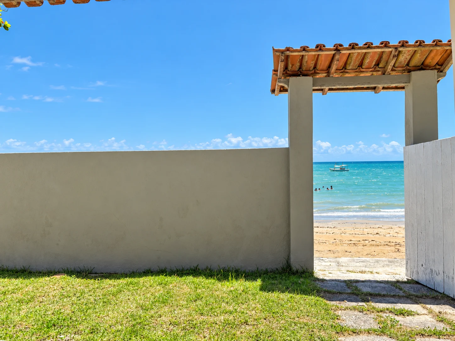 Portão da Casa Brisa do Mar aberto diretamente para a areia e o mar
